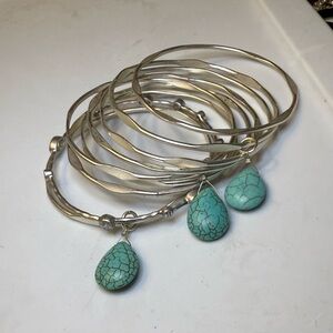 Set of 9 silver colored bangles with turquoise colored teardrop stones